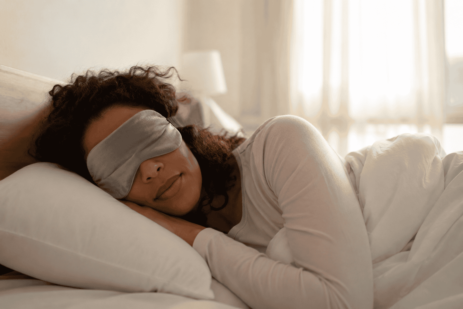 Persoon slaapt rustig met een slaapmasker op in een zacht verlichte slaapkamer
