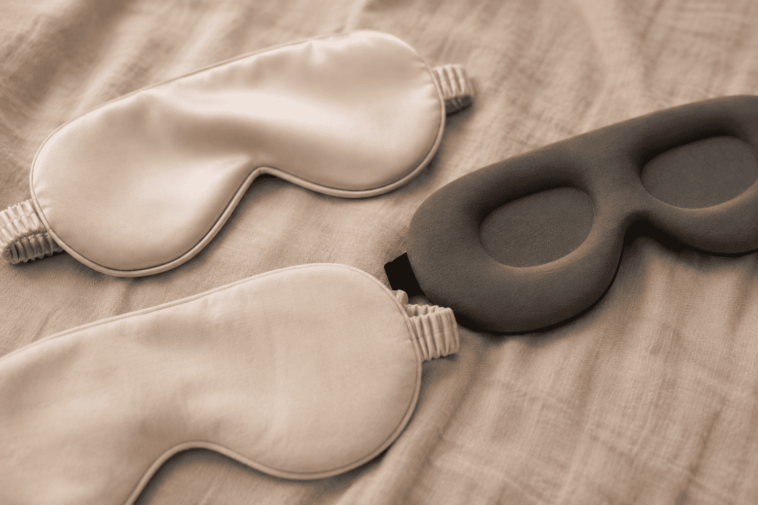Verschillende slaapmaskers van zijde en traagschuim naast elkaar op een neutrale ondergrond
